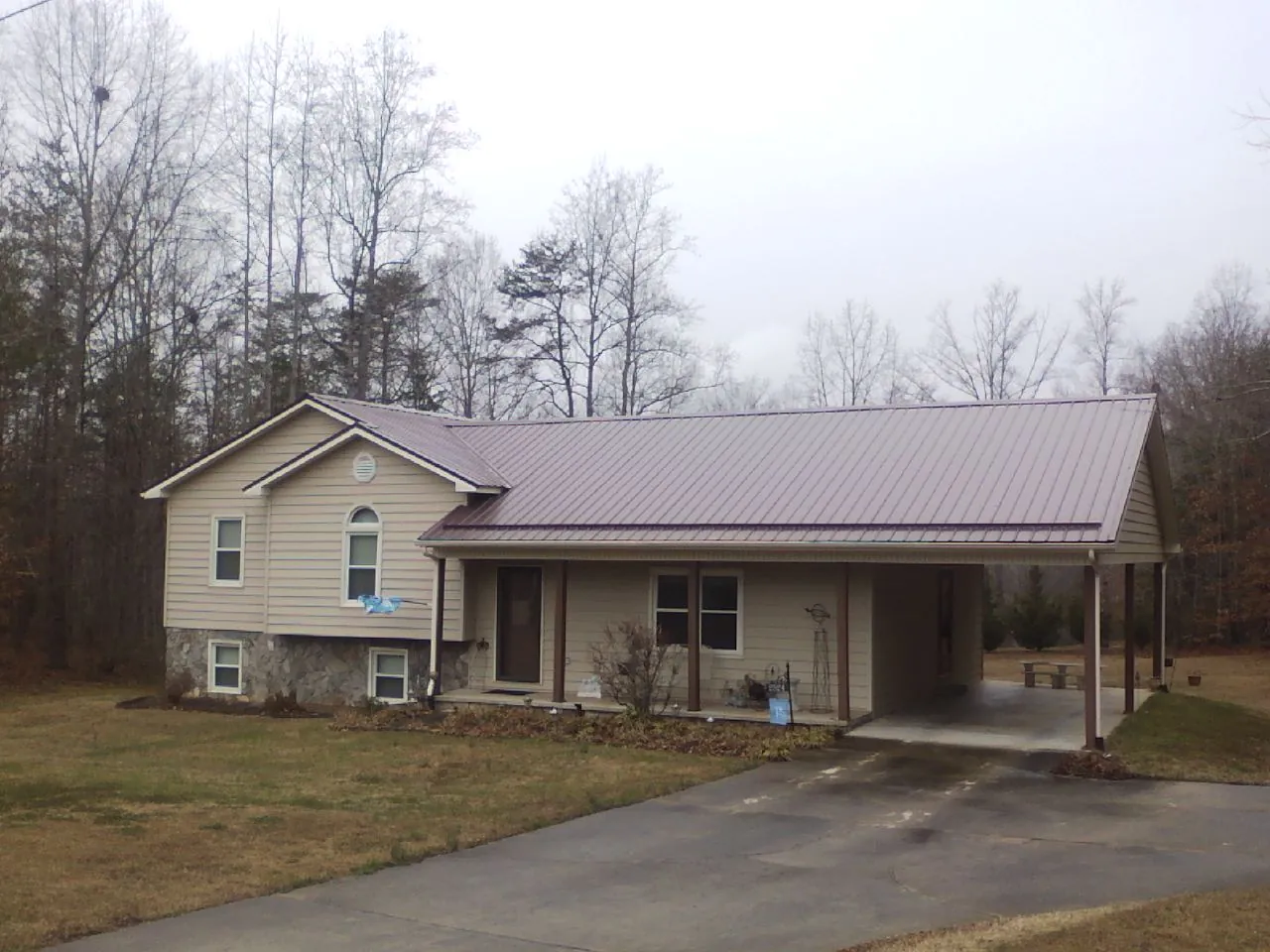 Burgundy metal roof on a tan split level home with an attached carport in Scottdale