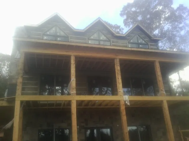 Dormers and porch framing on a large log home under construction — Roof Coating work by our crew in Scottdale