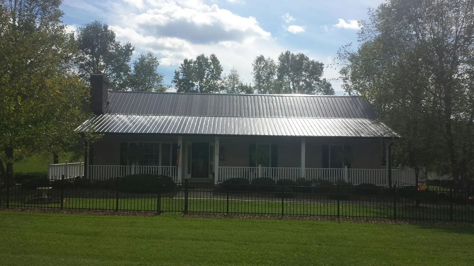 Gray metal roof on a brick ranch with a full width front porch — Gutter Guard Installation work by our crew in Scottdale